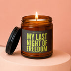 Amber glass candle with lit wick, lid ajar, reads "My Last Night of Freedom".