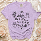 Comfort Colors t-shirt with "Holding Her Dress and Her Secrets" graphic.