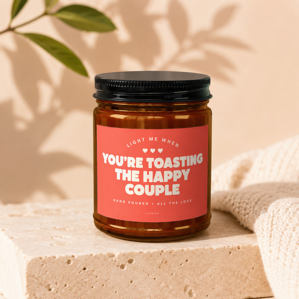 Amber jar candle with red label reading "You're Toasting the Happy Couple".