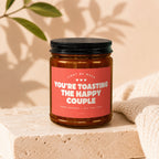 Amber jar candle with red label reading "You're Toasting the Happy Couple".