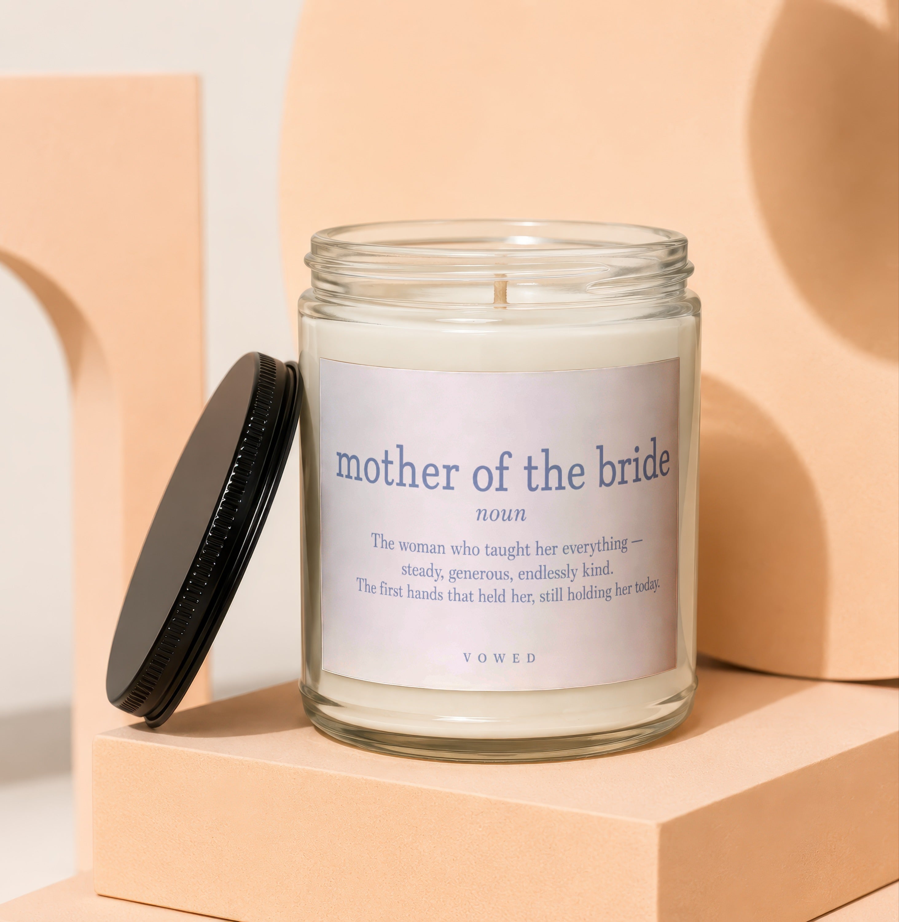 Glass candle with 'mother of the bride' definition label, lid ajar.