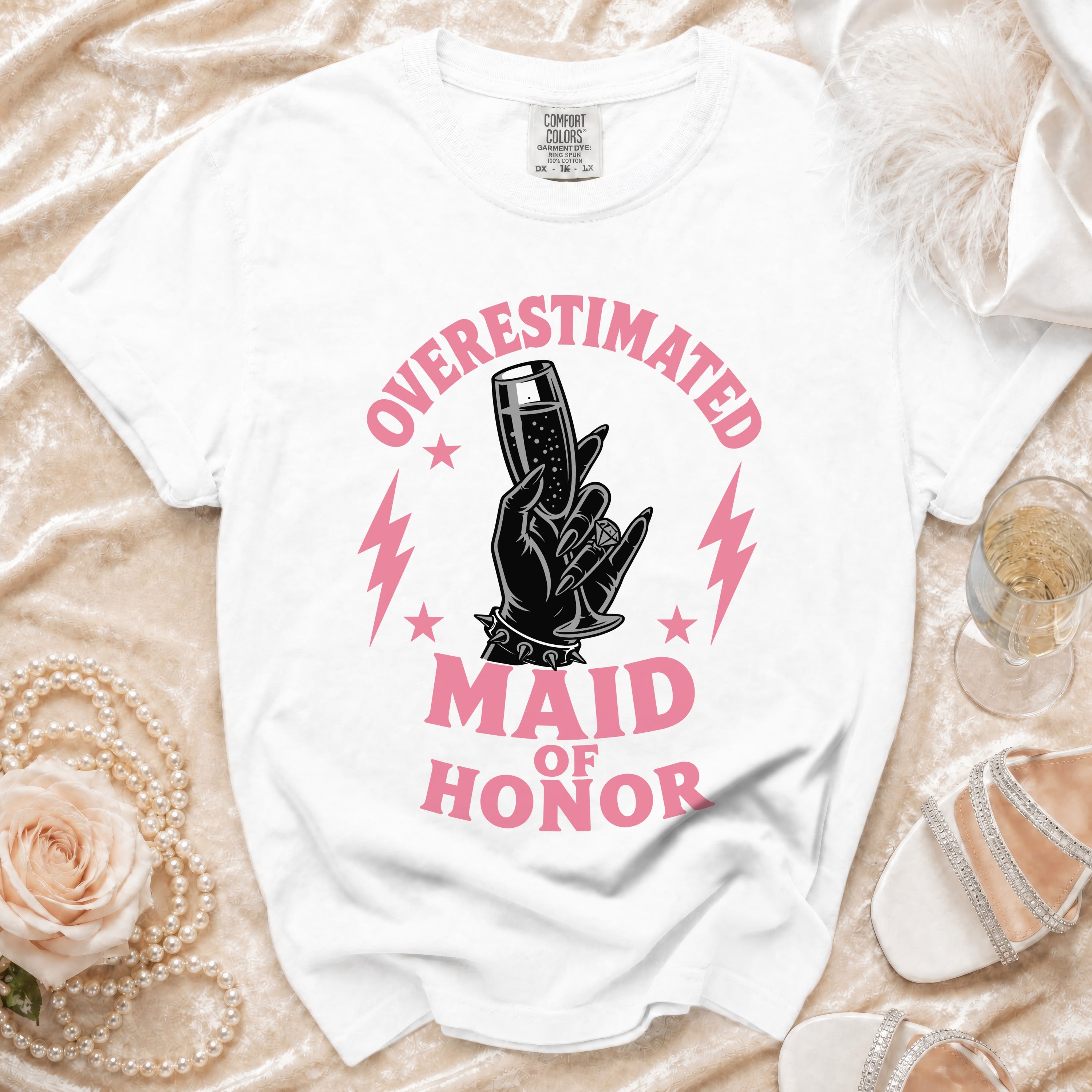 White t-shirt with pink "OVERESTIMATED MAID OF HONOR" graphic featuring a hand holding champagne.