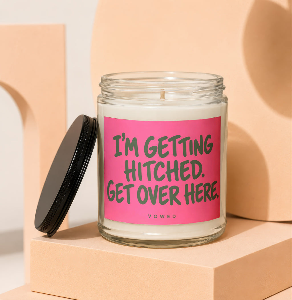 Glass candle with pink label reading "I'M GETTING HITCHED. GET OVER HERE."