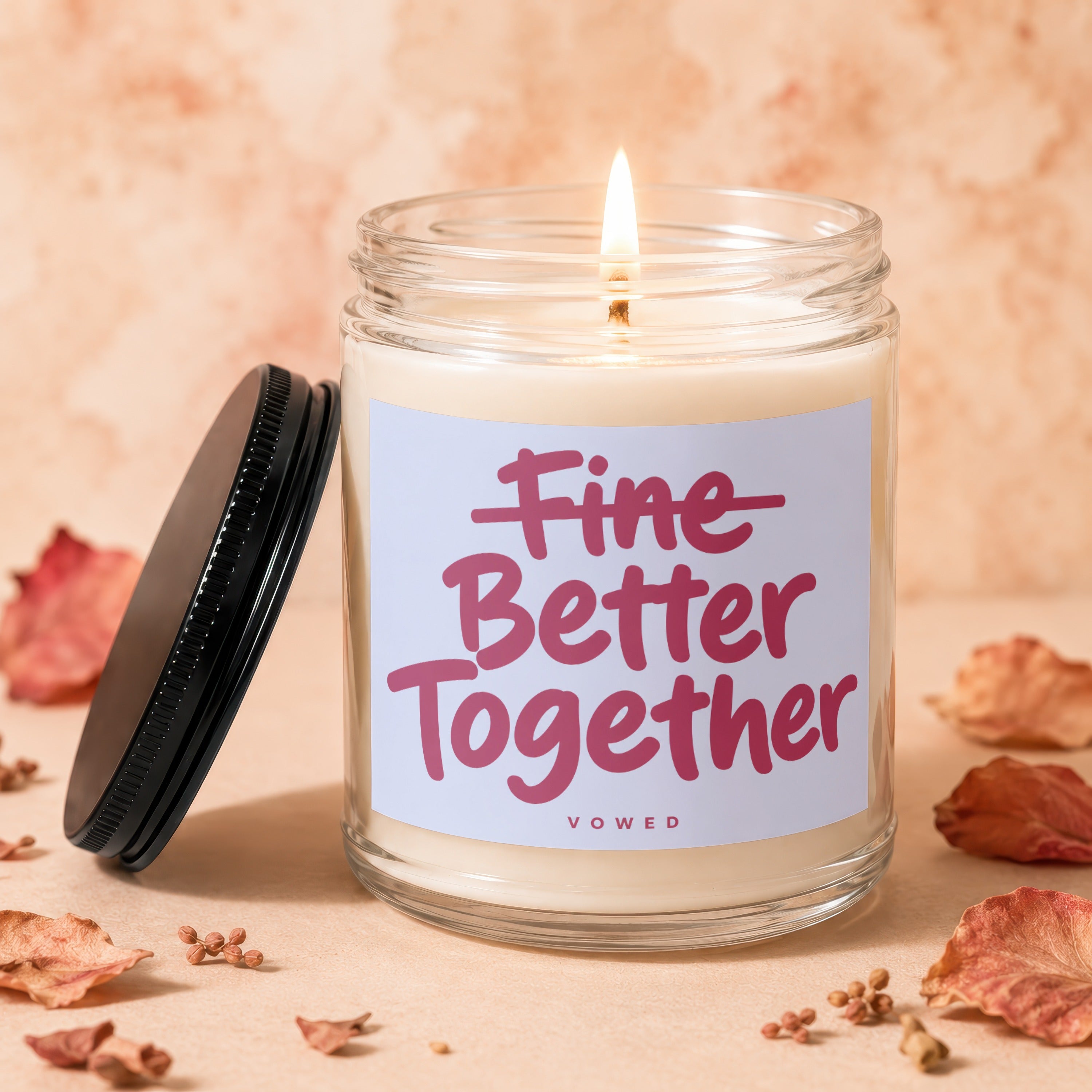 Glass jar candle with a lit wick and "Vowed Better Together" text on label.