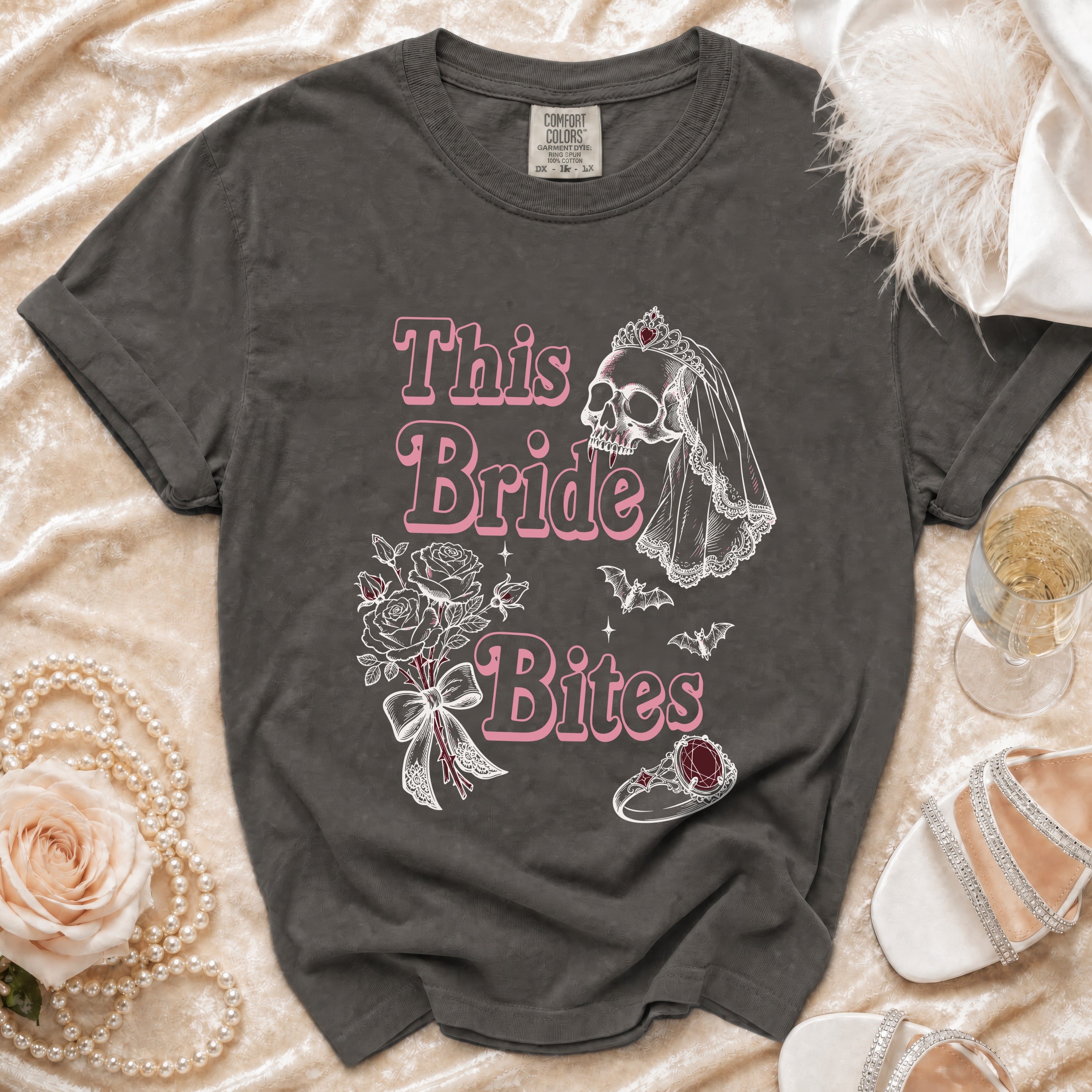 Dark grey t-shirt with pink text and graphics of a skull bride, flowers, bats, and a ring.