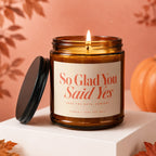 Amber candle with "So Glad You Said Yes" text and a lit wick.