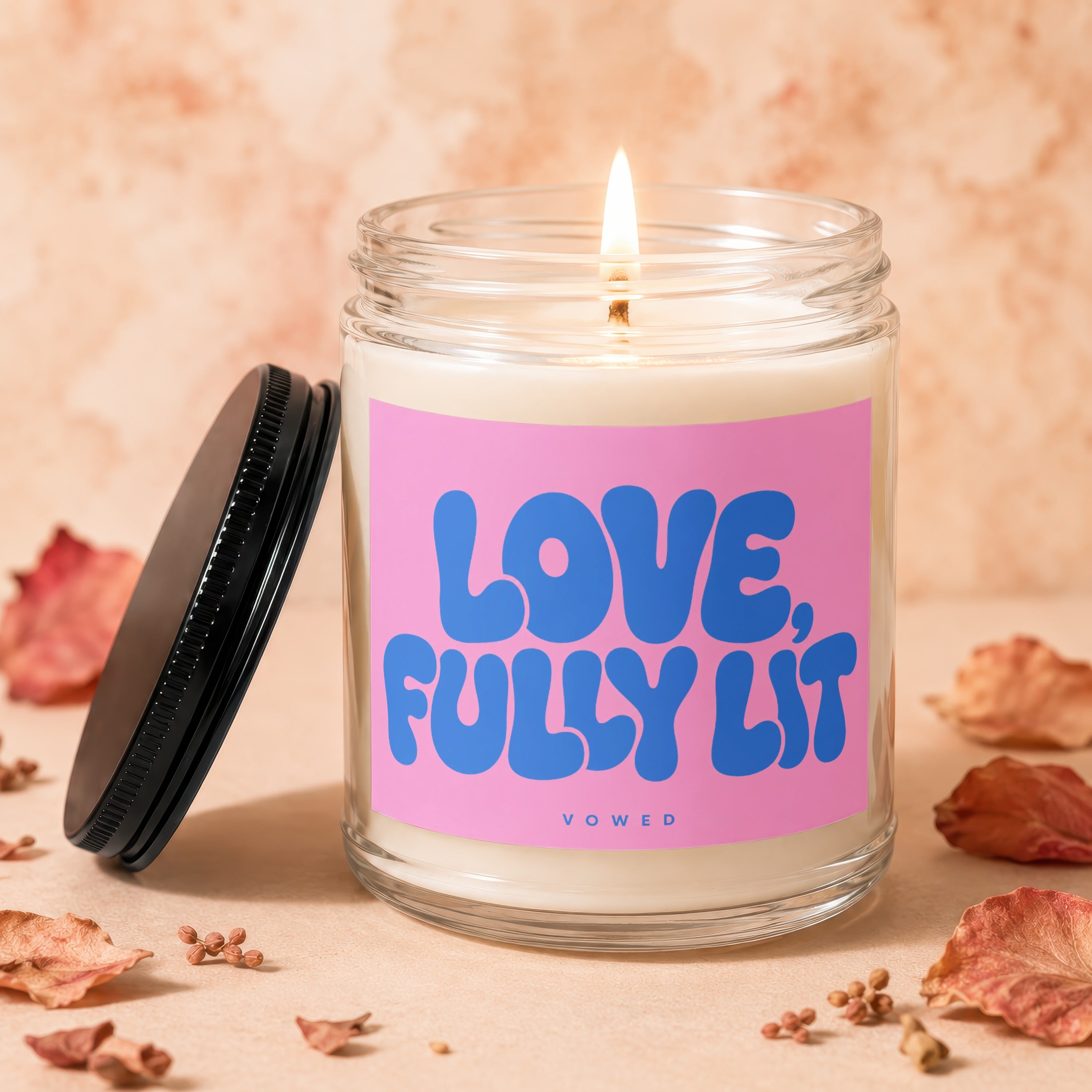 Candle with pink label reading "LOVE, FULLY LIT" and "VOWED".
