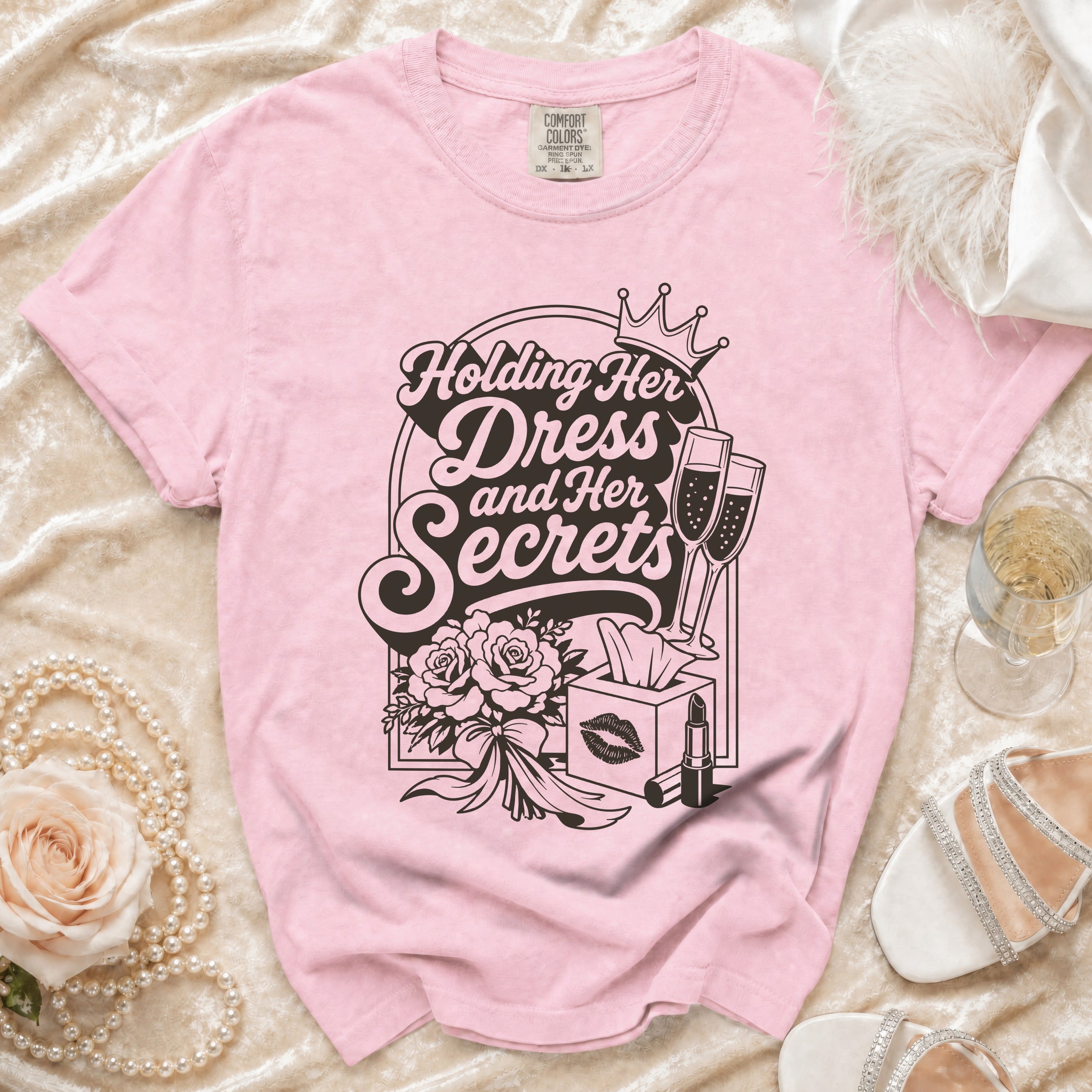 Pink t-shirt with "Holding Her Dress and Her Secrets" graphic, champagne glasses, roses, and lipstick.
