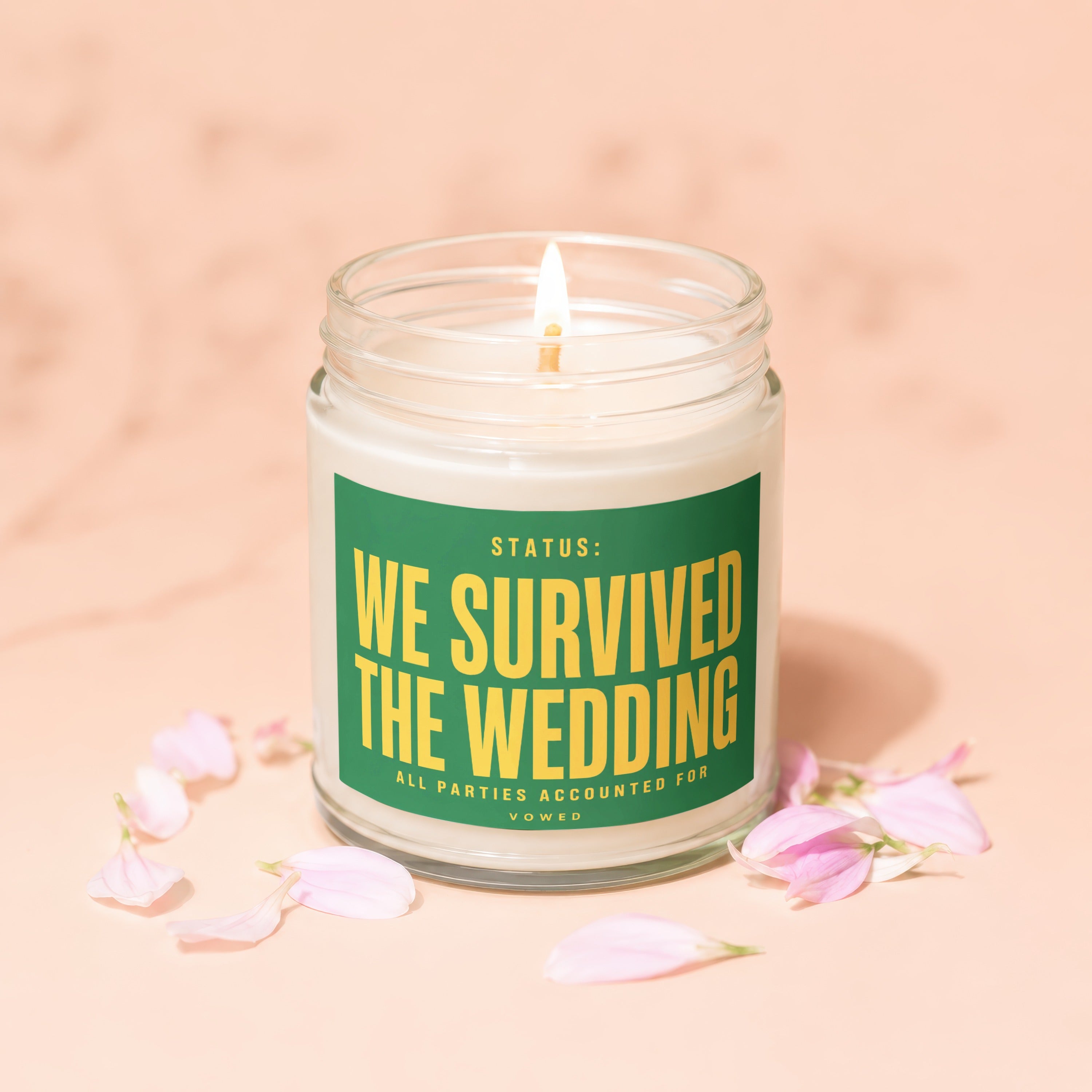 Lit candle in a jar with a green label reading "Status: We Survived The Wedding".