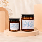 Two amber glass candles with black lids and "Married the plot twist" text.