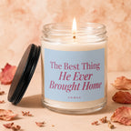 Lit candle in glass jar with blue label reading "The Best Thing He Ever Brought Home".