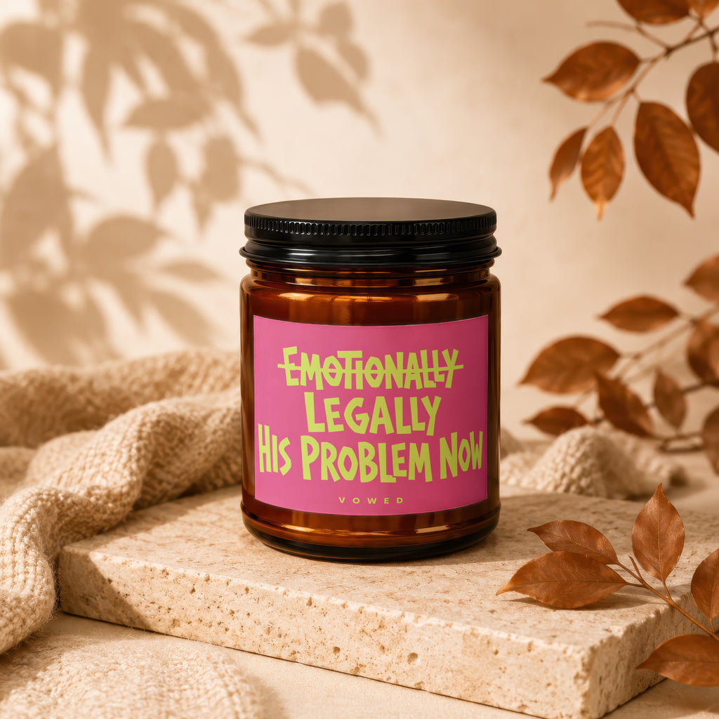 Amber jar candle with a pink label reading "Emotionally Legally His Problem Now".