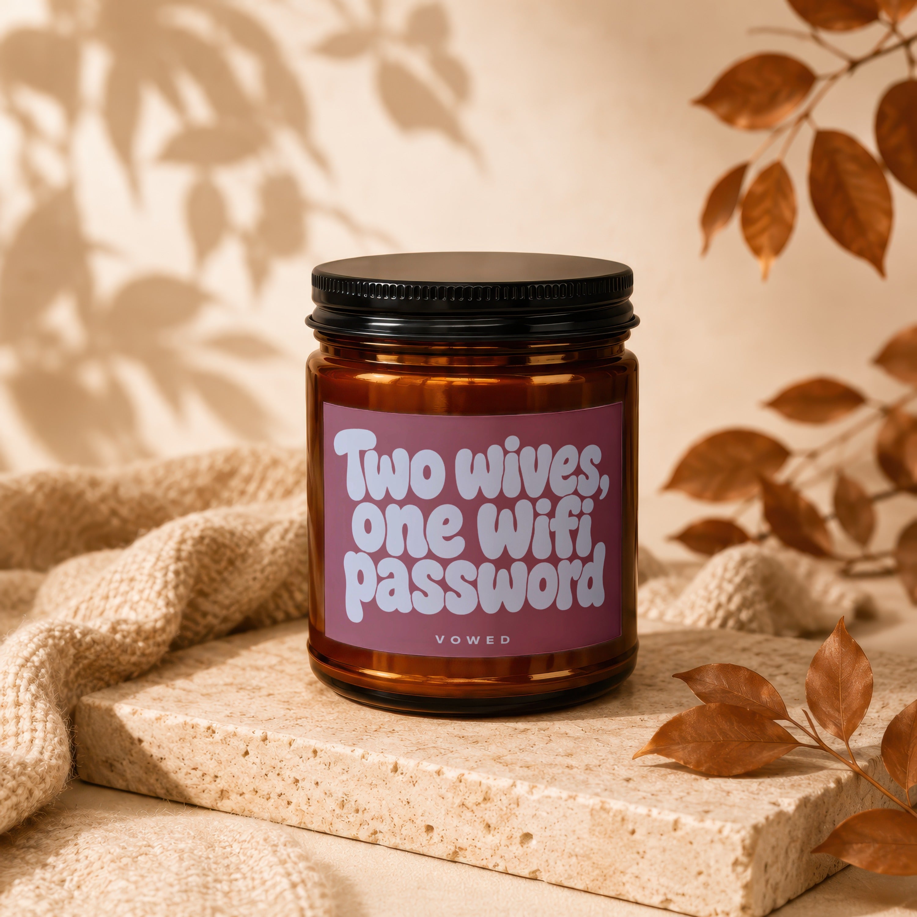 Amber candle with pink label reading "Two wives, one Wifi password VOWED".