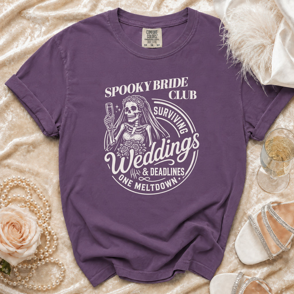 Purple t-shirt with skeleton bride graphic: "Spooky Bride Club Surviving Weddings & Deadlines One Meltdown".