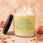 Lit soy candle in glass jar with yellow label reading "Our Favorite Plot Twist"