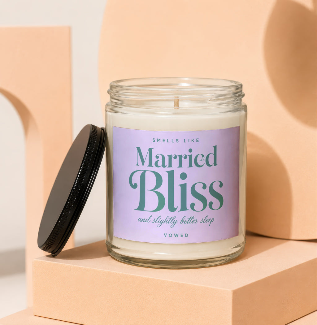 Glass candle labeled "Smells like Married Bliss and slightly better sleep" by Vowed.