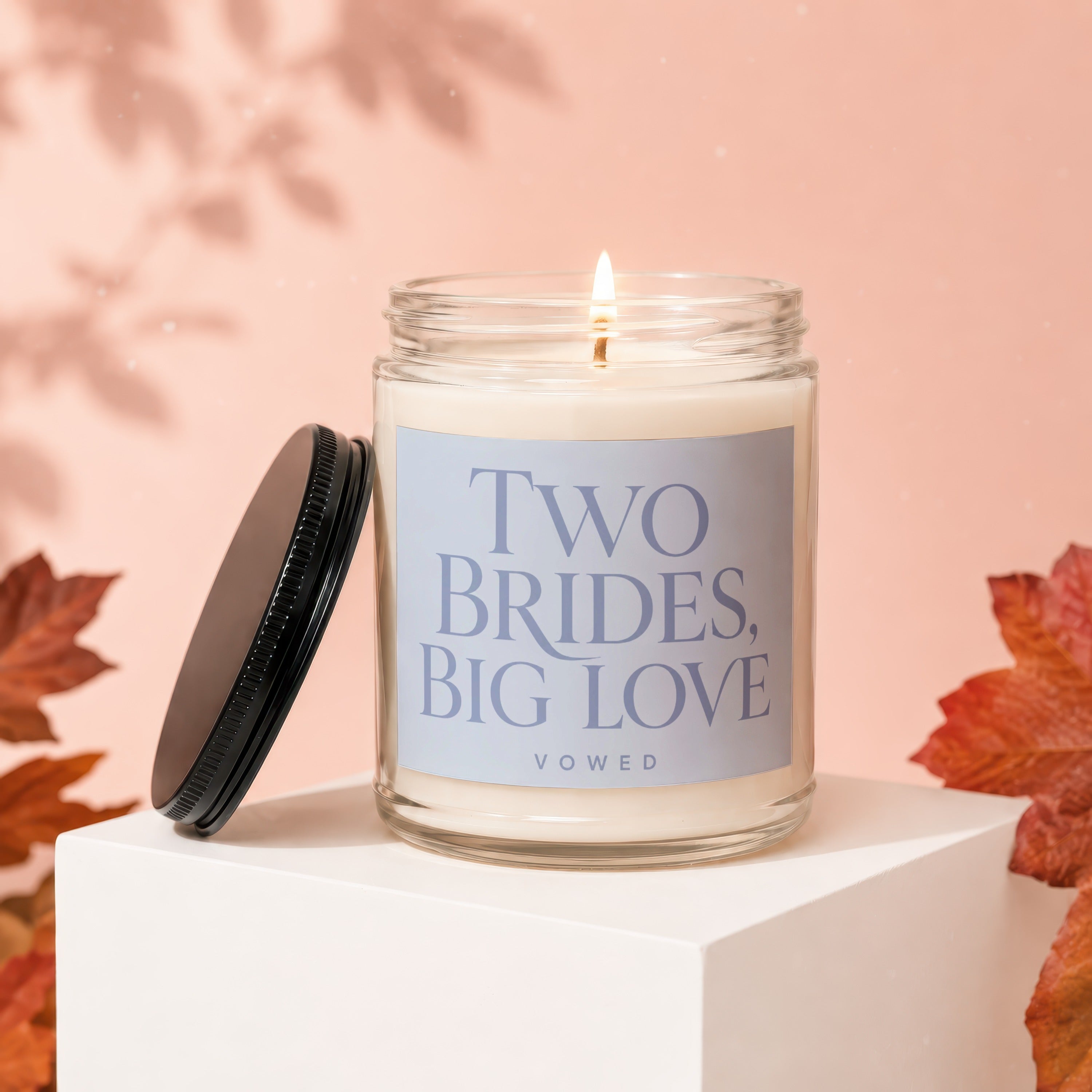 Lit candle in a glass jar with "Two Brides, Big Love" text and Vowed logo.