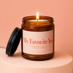 Amber jar candle with lit wick and black lid, "My Favorite Yes" label.