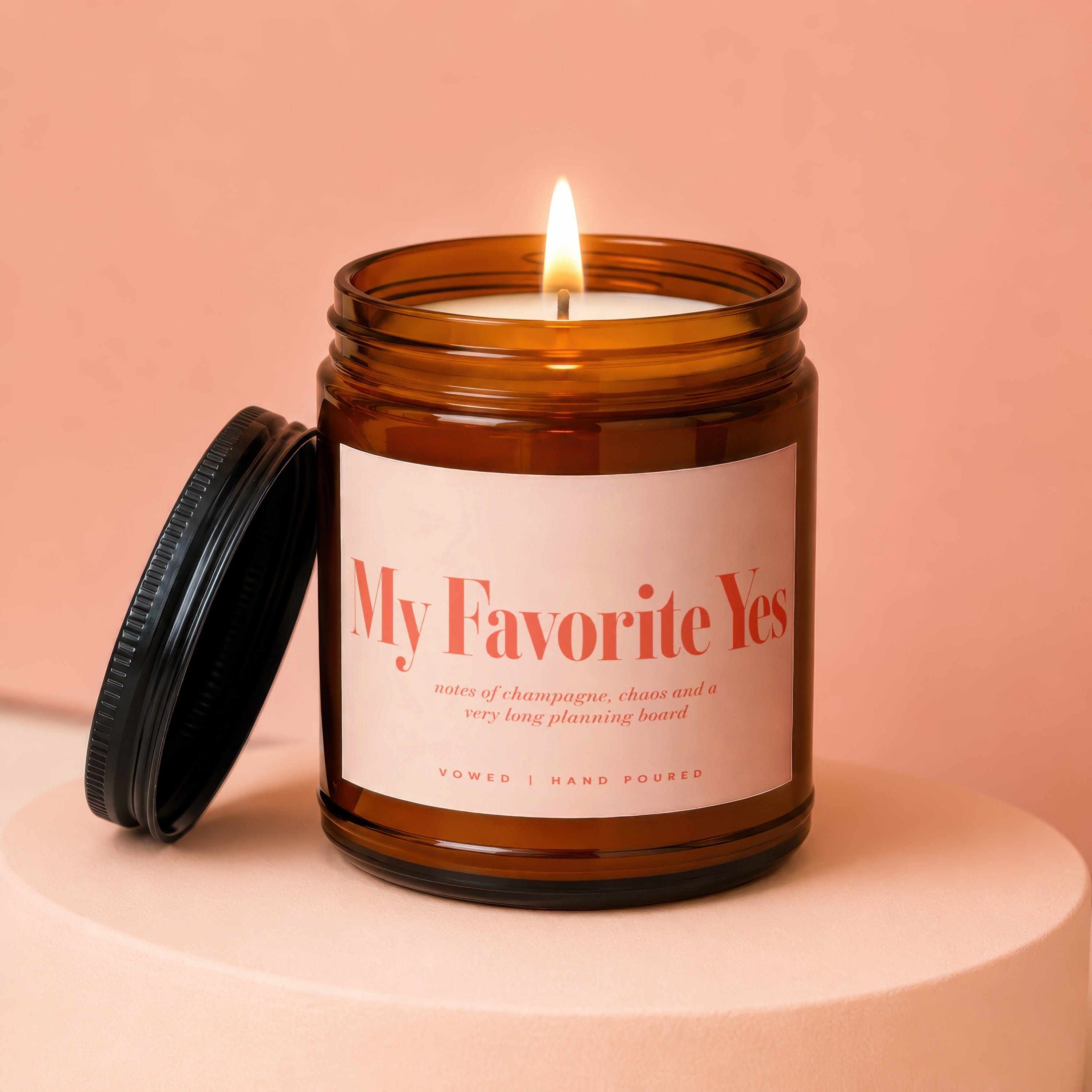 Amber jar candle with lit wick and black lid, "My Favorite Yes" label.