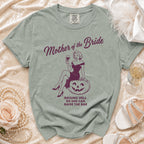 "Mother of the Bride" shirt with a pin-up graphic and text "Raising Hell So She Can Raise the Bar".