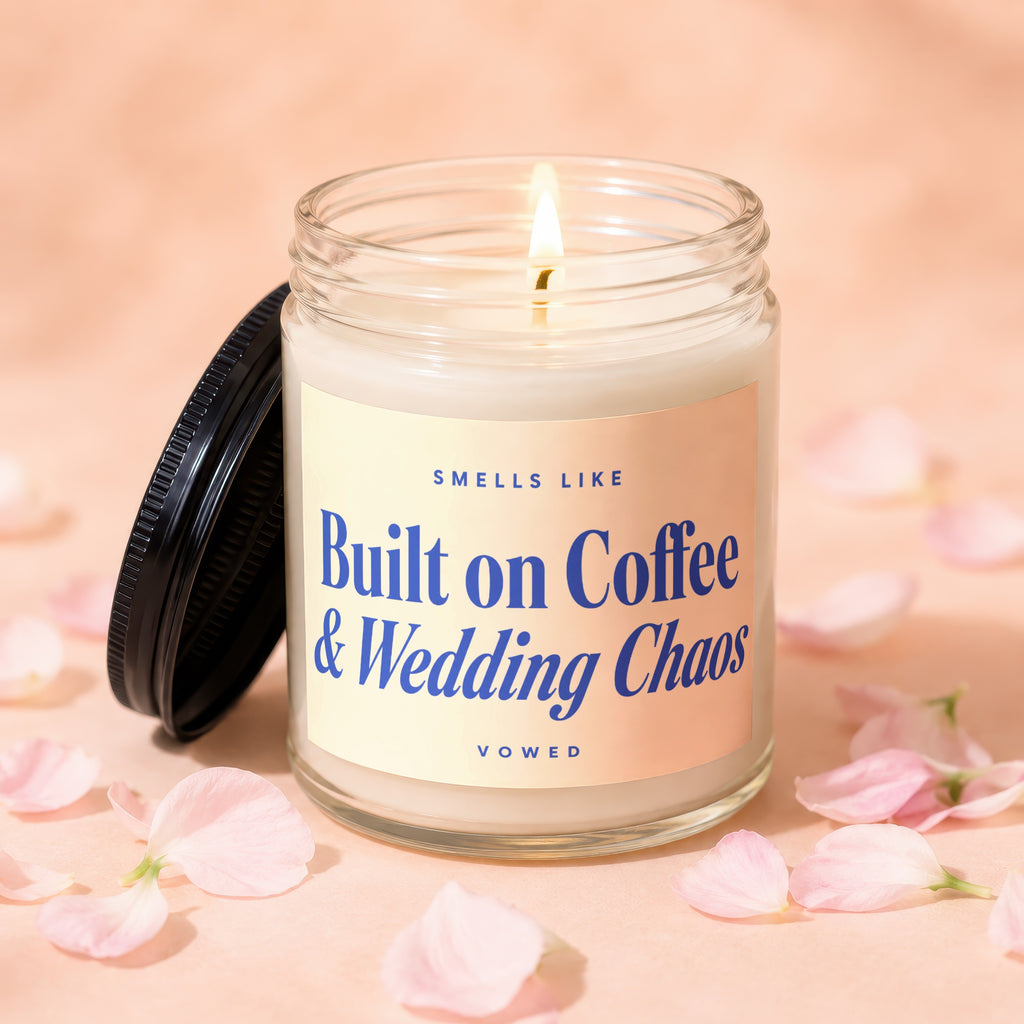 Glass jar candle with light burning, reads "Smells Like Built on Coffee & Wedding Chaos VOWED".