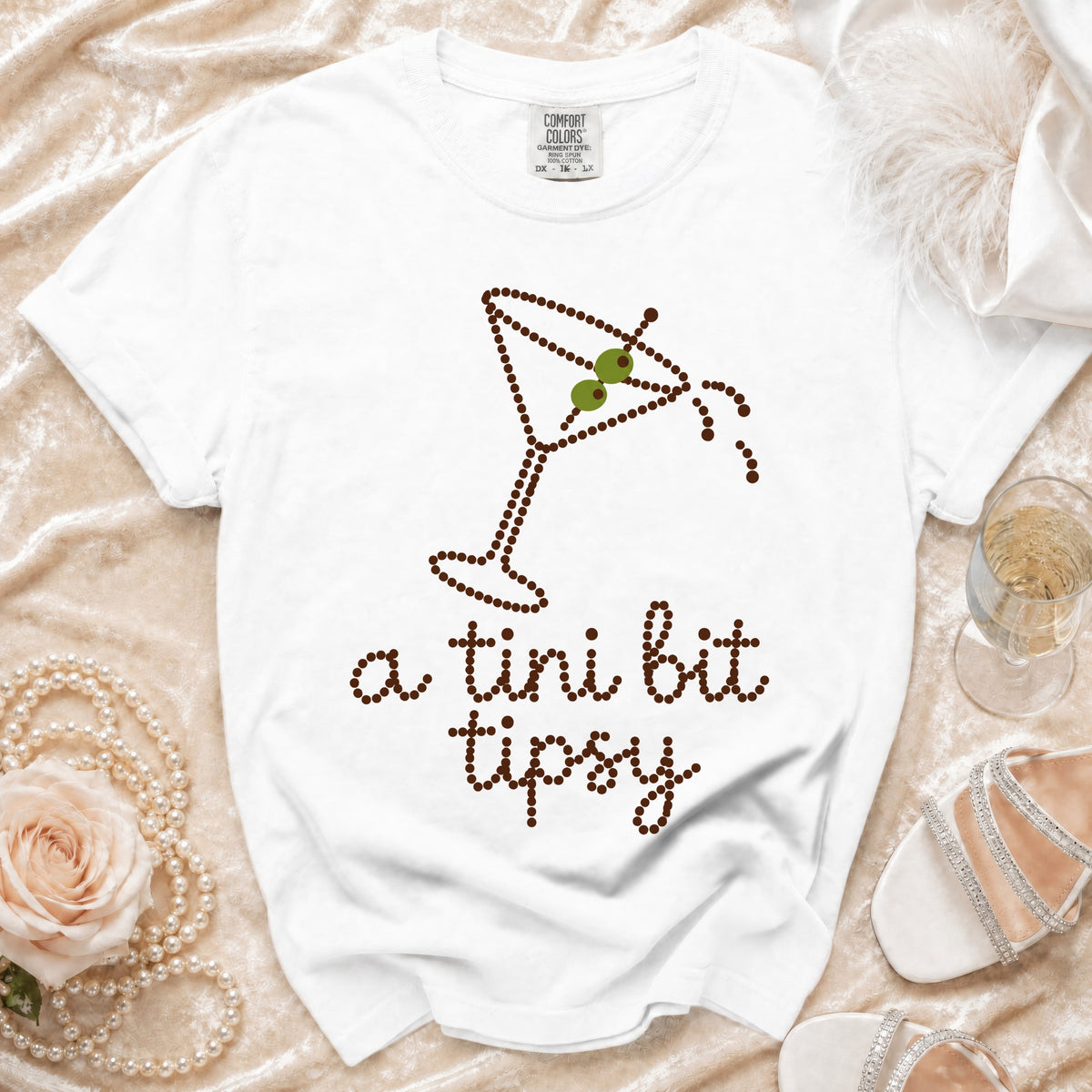White t-shirt with martini glass graphic and "a tini bit tipsy" text.