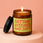 Amber candle in a jar with a lit wick and lid slightly ajar, text reads "Getting Hitched and Sh*t".