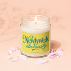 Scented candle with "Newlyweds obviously" text on yellow label and pink petals.