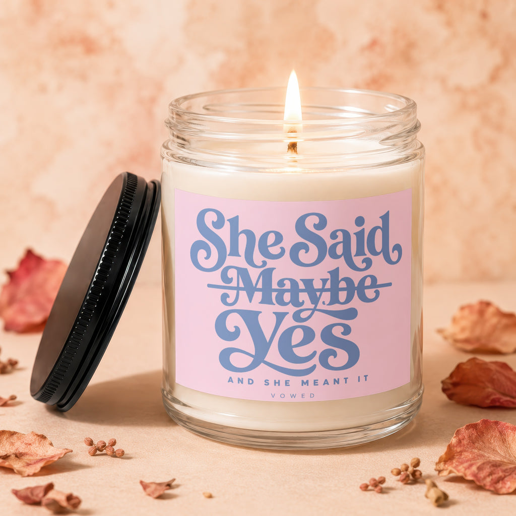 Candle with pink label reading "She Said Maybe Yes And She Meant It VOWED".