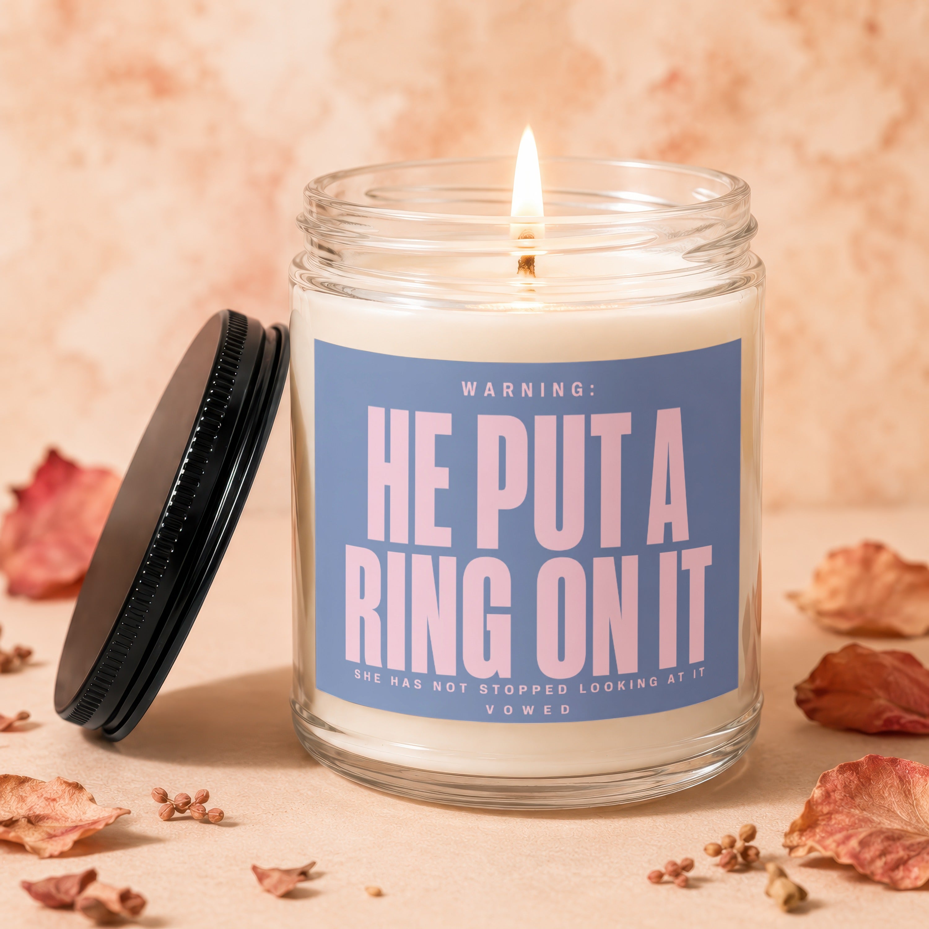 Glass candle with blue label saying "Warning: He put a ring on it".