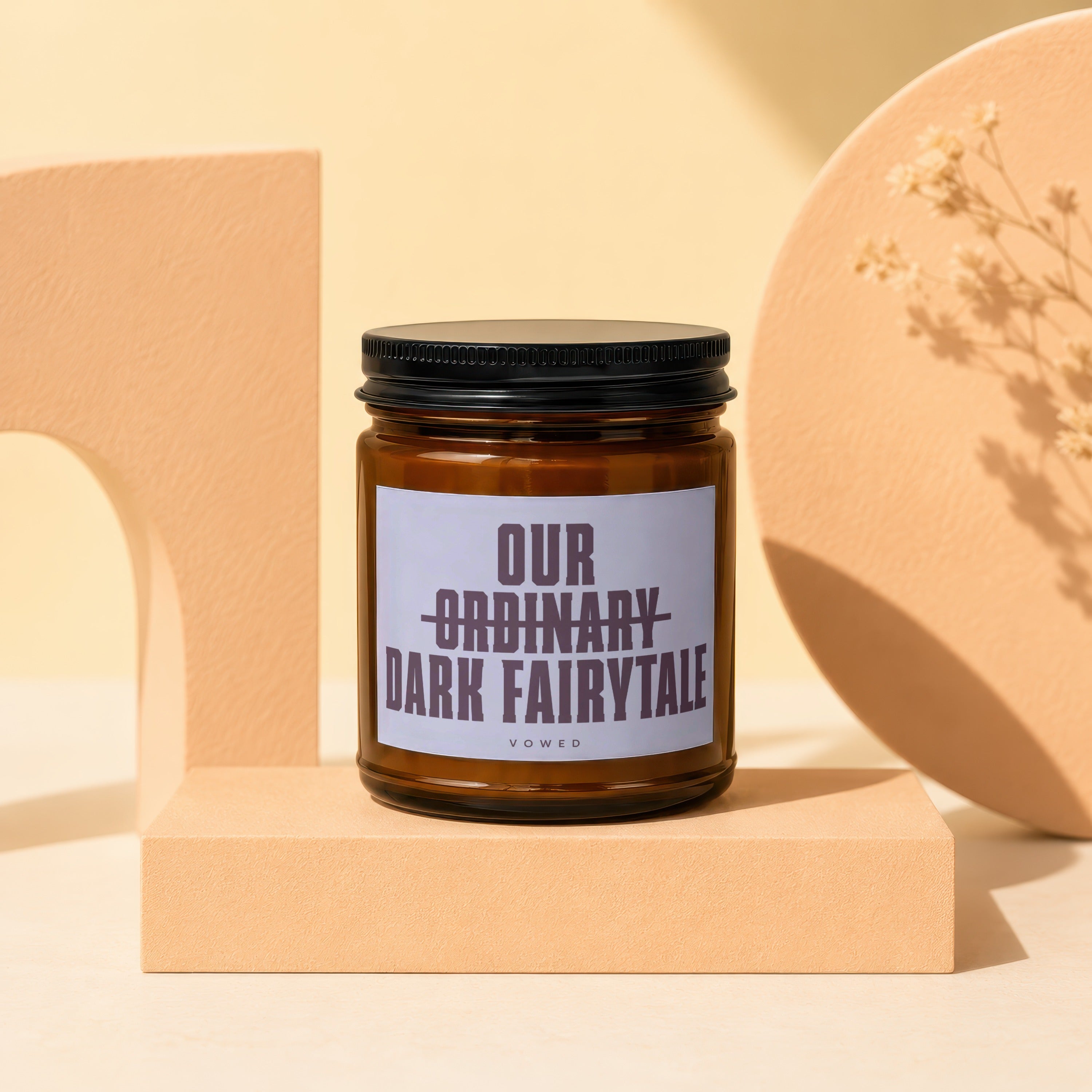 Amber candle in glass jar with black lid, reads "Our Ordinary Dark Fairytale."