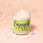 Engaged AF candle in a jar with a lit wick and pink petals.