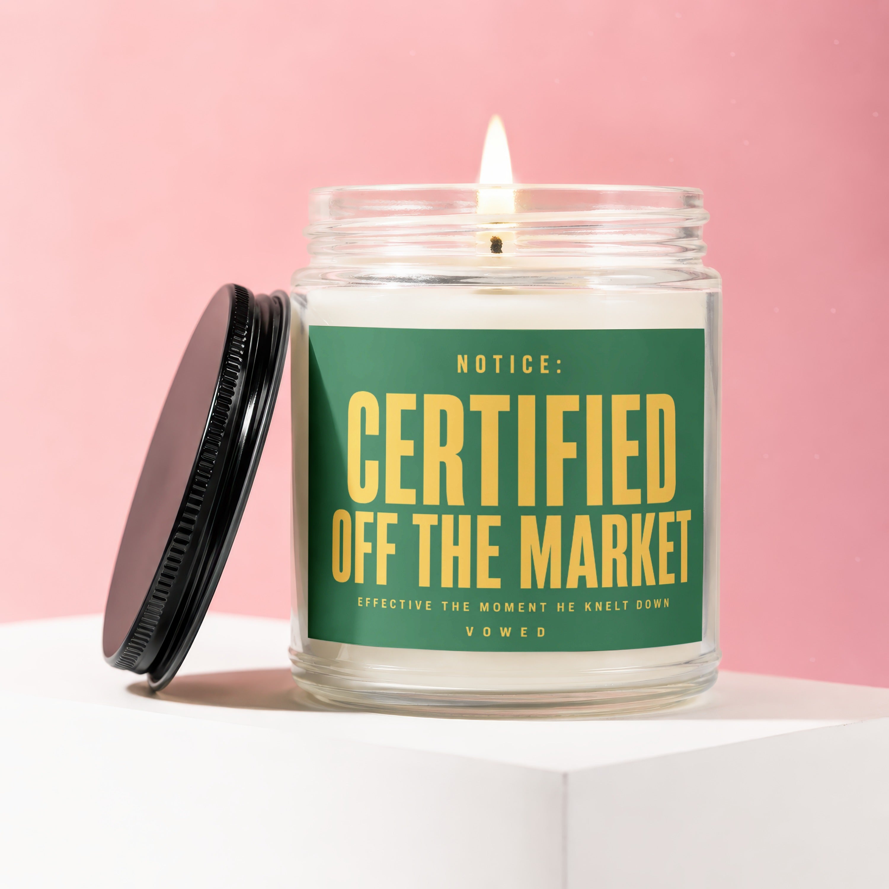 Glass candle with green label saying "Certified Off The Market" on a pink background.