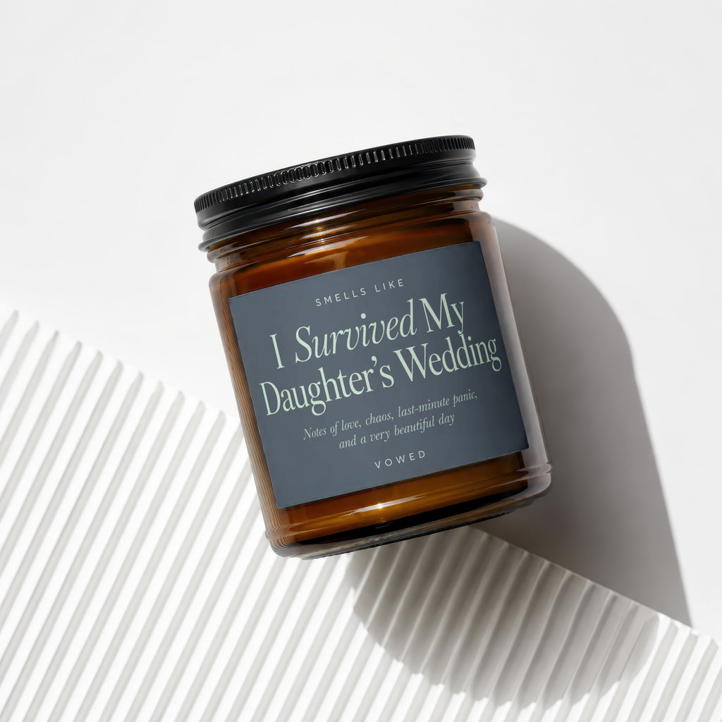 Amber glass candle with dark label reading "I Survived My Daughter's Wedding."