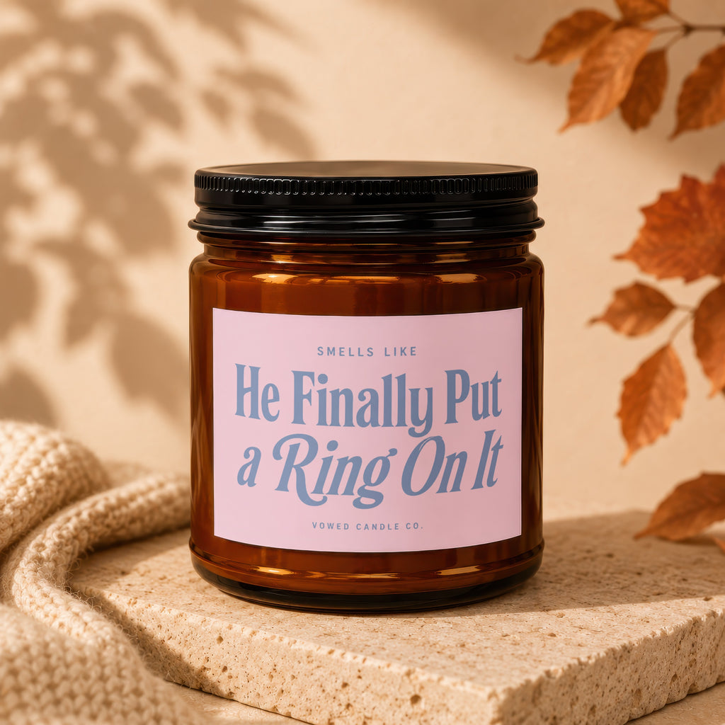 Amber jar candle with pink label reading "He Finally Put a Ring On It"