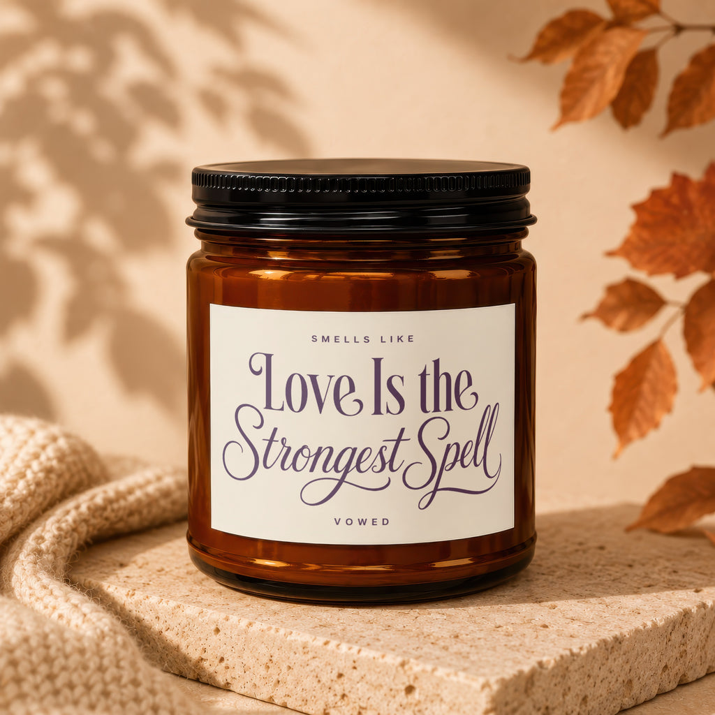 Amber candle with black lid, label reads "Love Is the Strongest Spell".