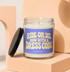 Clear glass candle with purple label reading "RIDE OR DIE, NOW WITH A DRESS CODE VOWED".