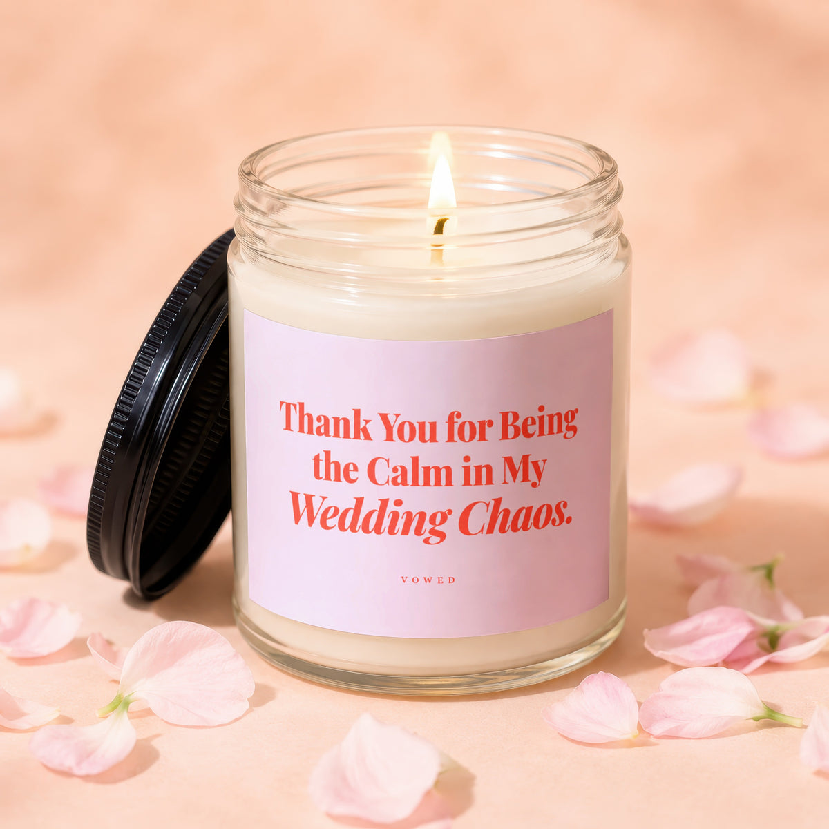 Glass candle with lit wick, pink label reading "Thank You for Being the Calm in My Wedding Chaos."