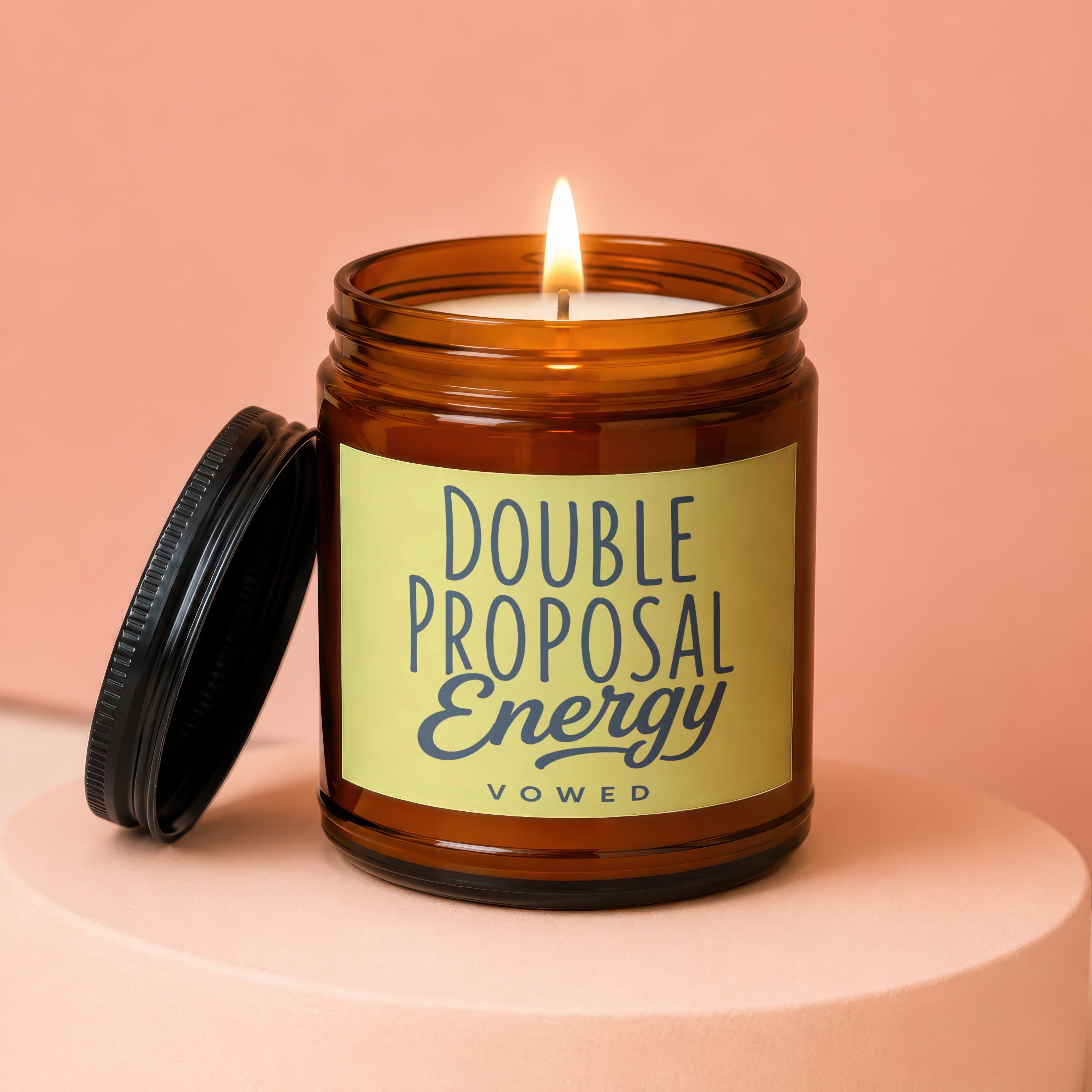 Amber jar candle with black lid displaying "DOUBLE PROPOSAL Energy VOWED."