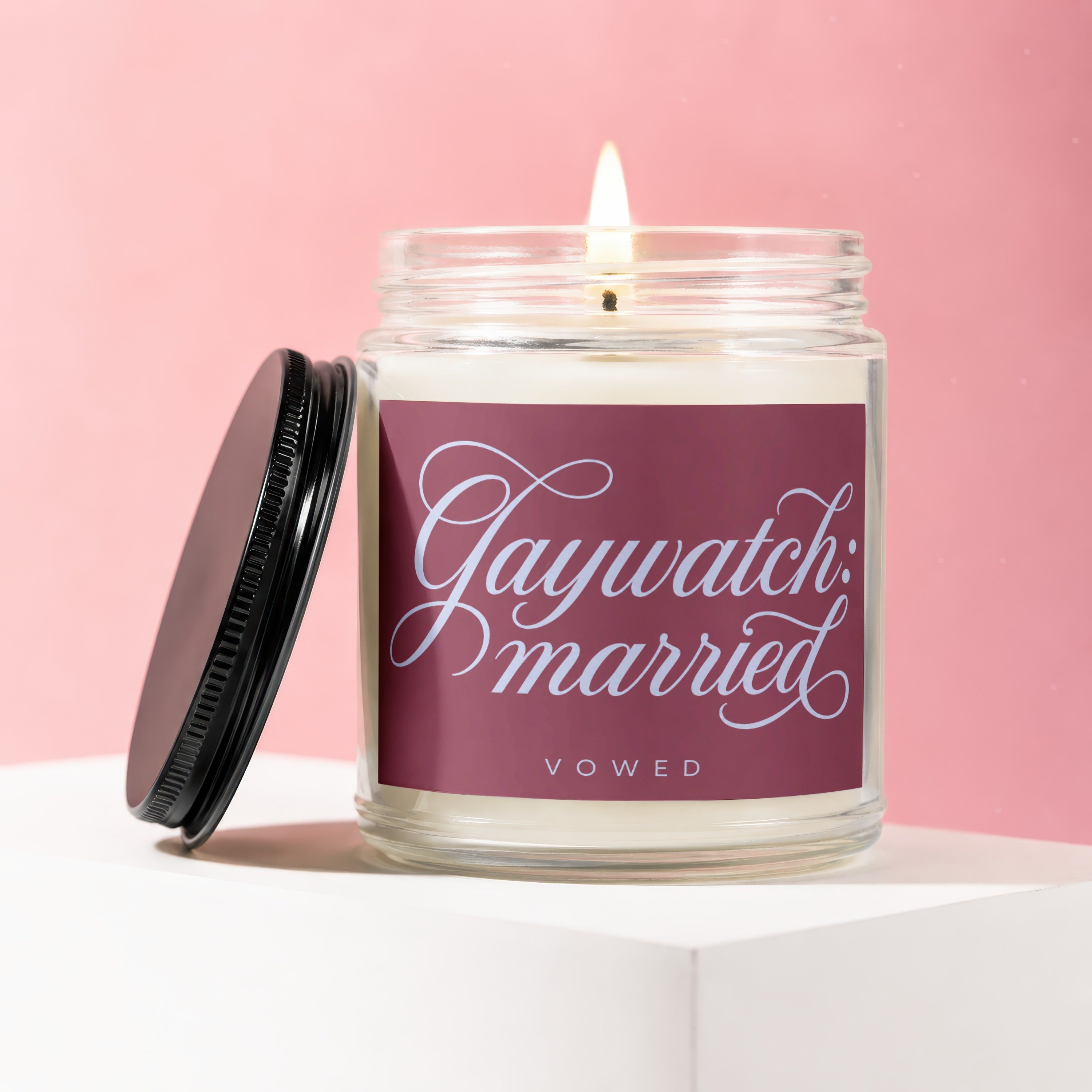Glass jar candle with a lit wick and black lid, labeled "Gaywatch: married".