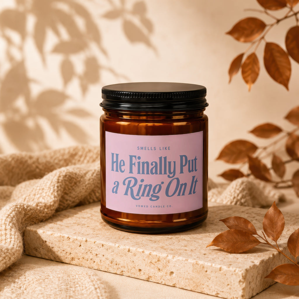 Brown candle with pink label reading "He Finally Put a Ring On It"