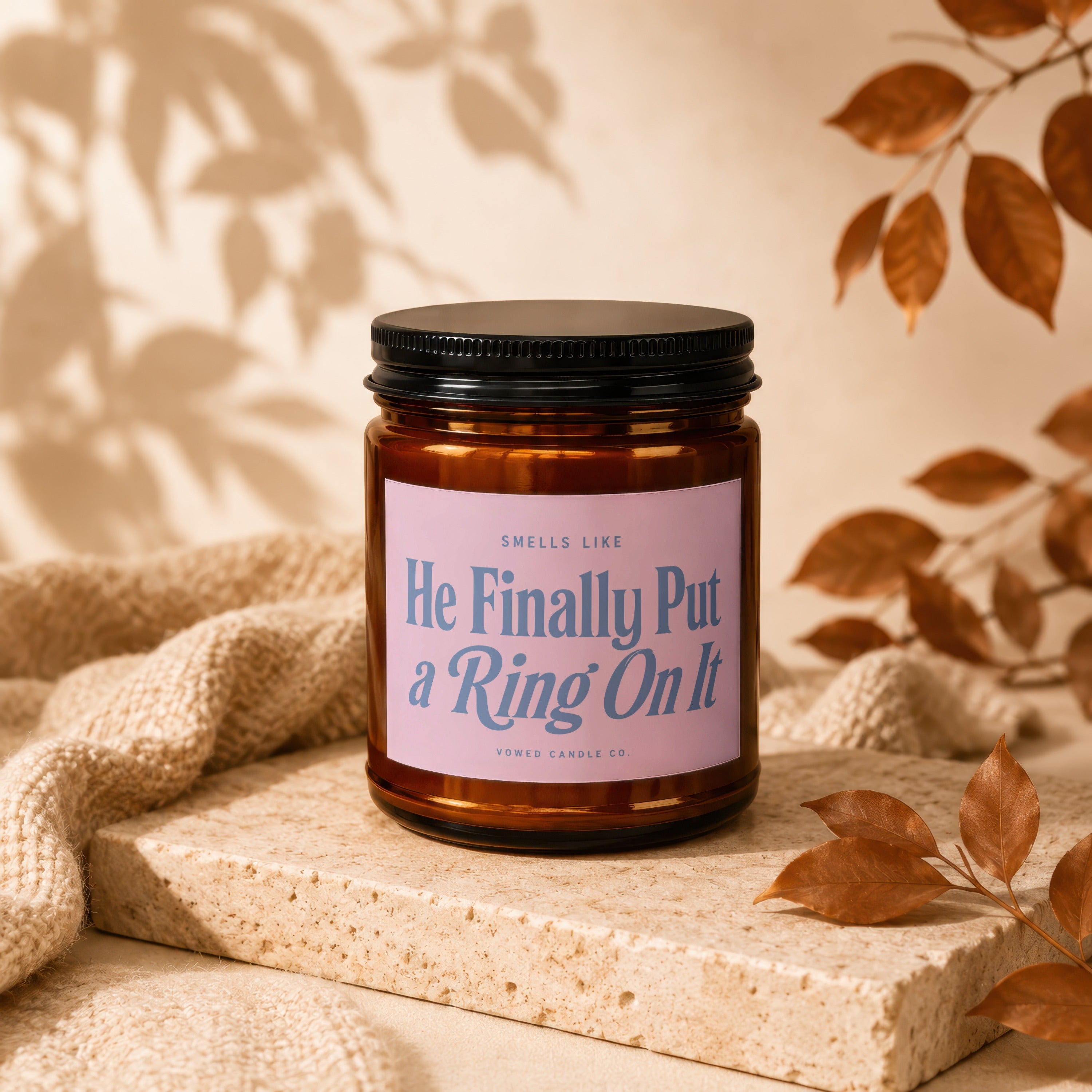 Brown candle with pink label reading "He Finally Put a Ring On It"