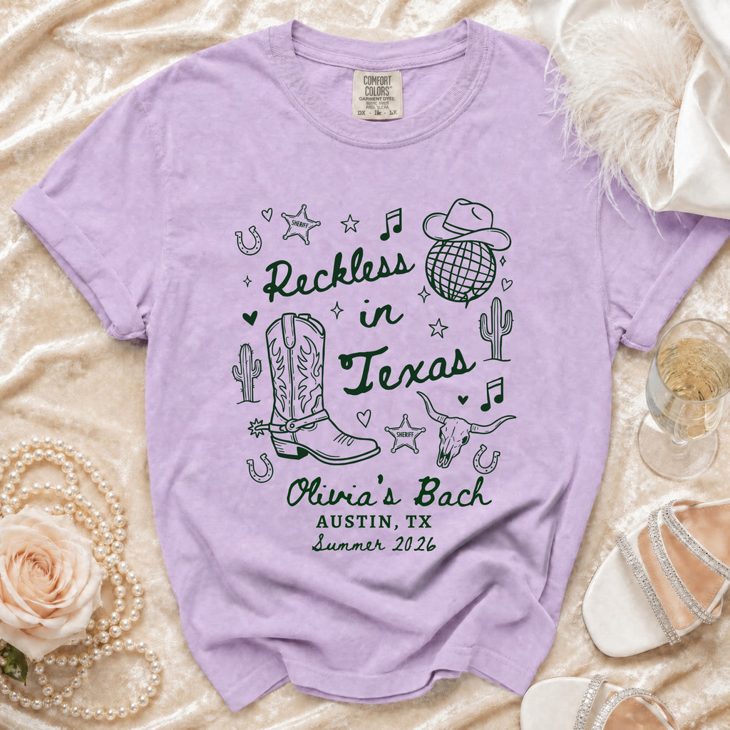 Lavender t-shirt with "Reckless in Texas" and cowboy graphics.