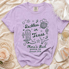 Lavender t-shirt with "Reckless in Texas" and cowboy graphics.