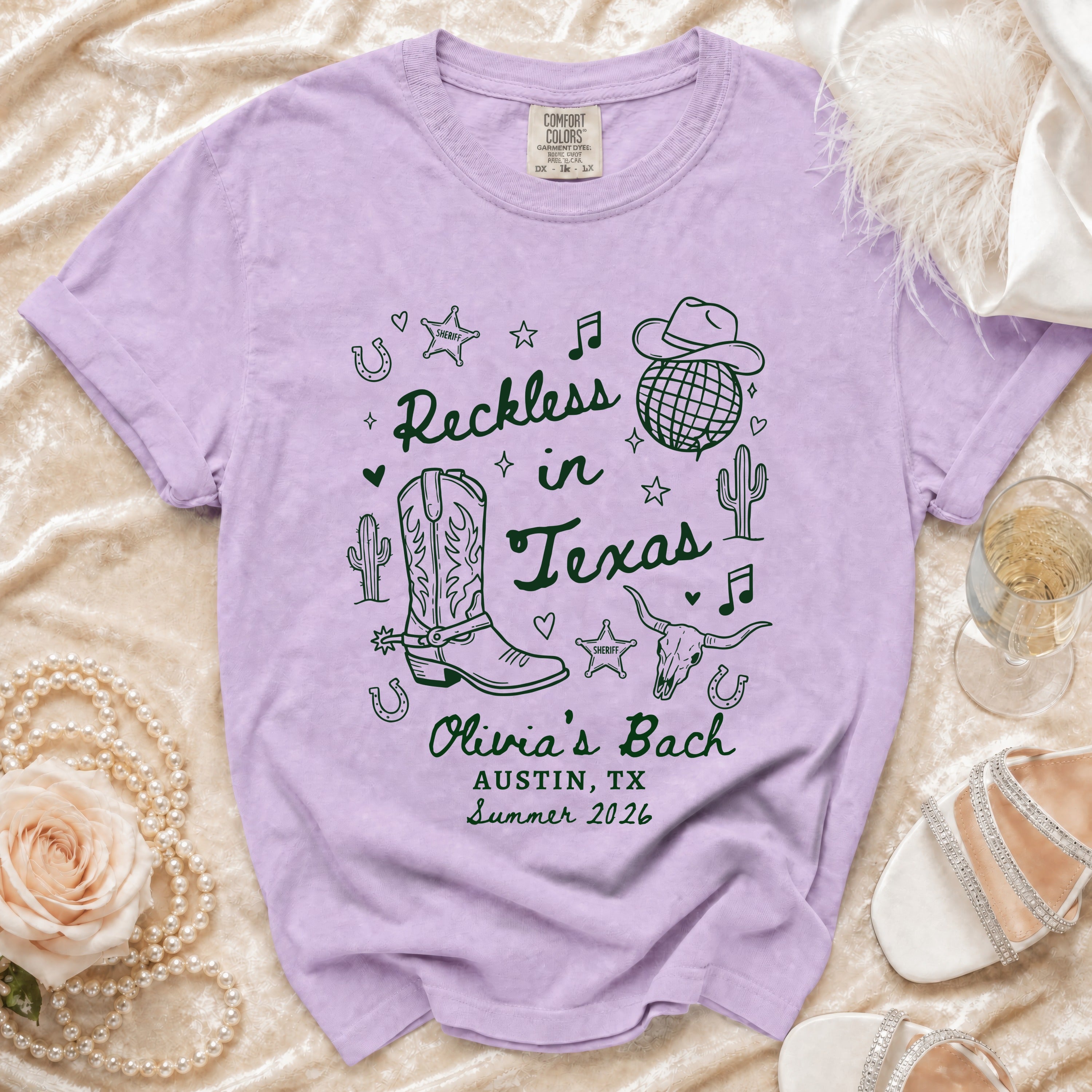 Lavender t-shirt with "Reckless in Texas" and cowboy graphics.