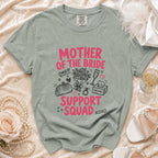 T-shirt with "Mother of the Bride Support Squad" in pink lettering and graphic icons.