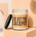 Jar candle with a yellow label reading "SMELLS LIKE HE HIT THE JACKPOT".
