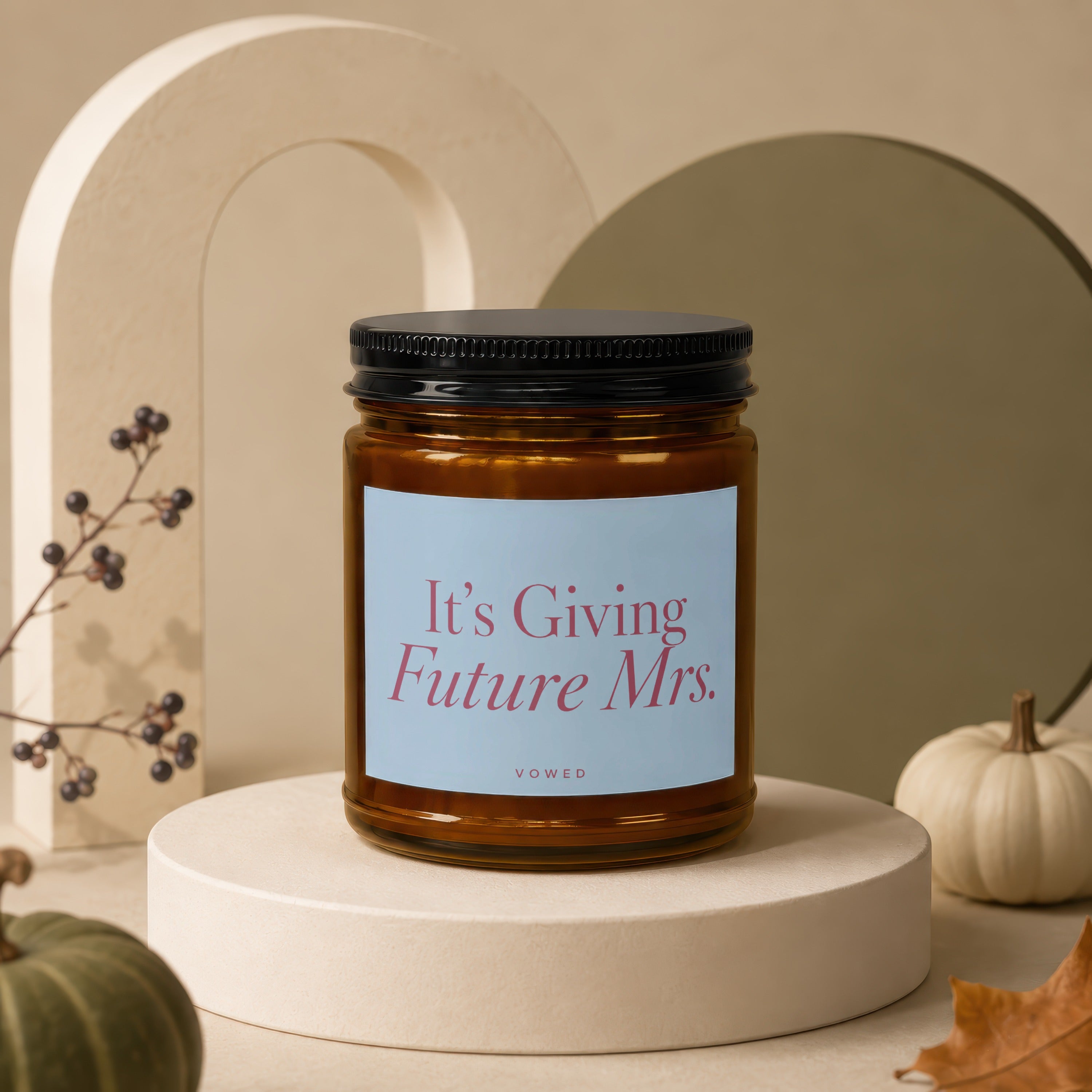 Candle with a label reading "It's Giving Future Mrs." on a pedestal.