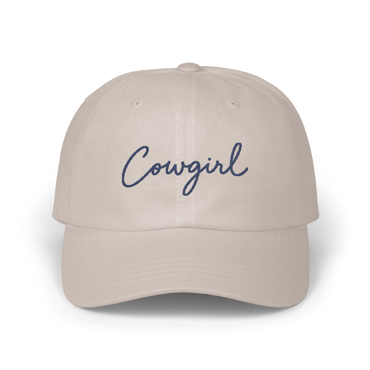 Light beige baseball cap with the word Cowgirl embroidered in navy blue cursive script.