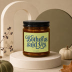 Amber glass candle with black lid, inscribed "Both of us said yes" and "vowed".